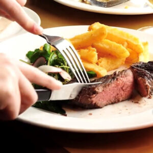 Black handled steak knife cutting into a juicy steak